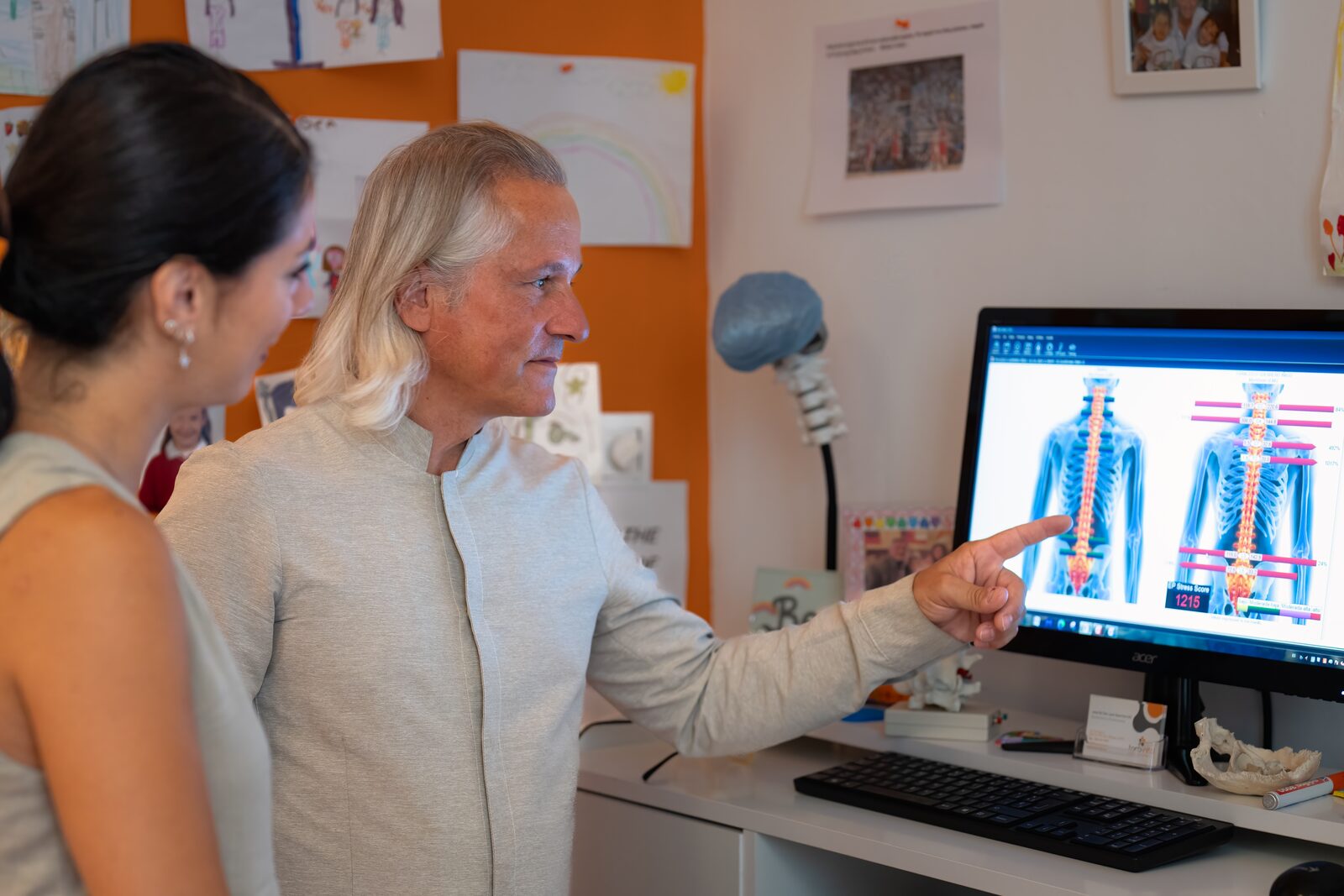 Scoliosis: computerised postural analysis in Málaga José De San Juan Guerrero, D.C., going through a computerised postural analysis on screen with a patient in his Málaga clinic